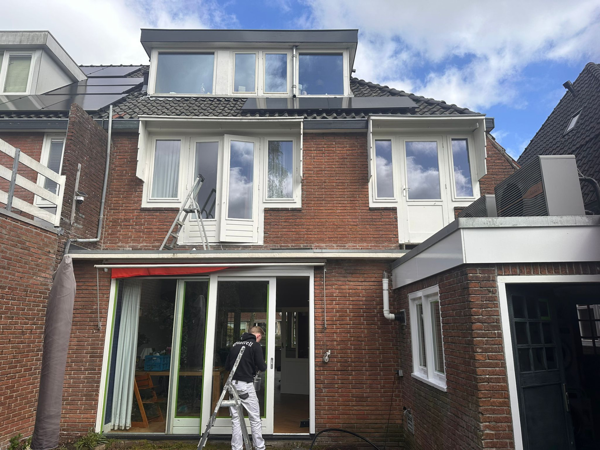 Voorgevel aan de Troelstraweg tijdens het buitenschilderwerk met schilder op een trap
