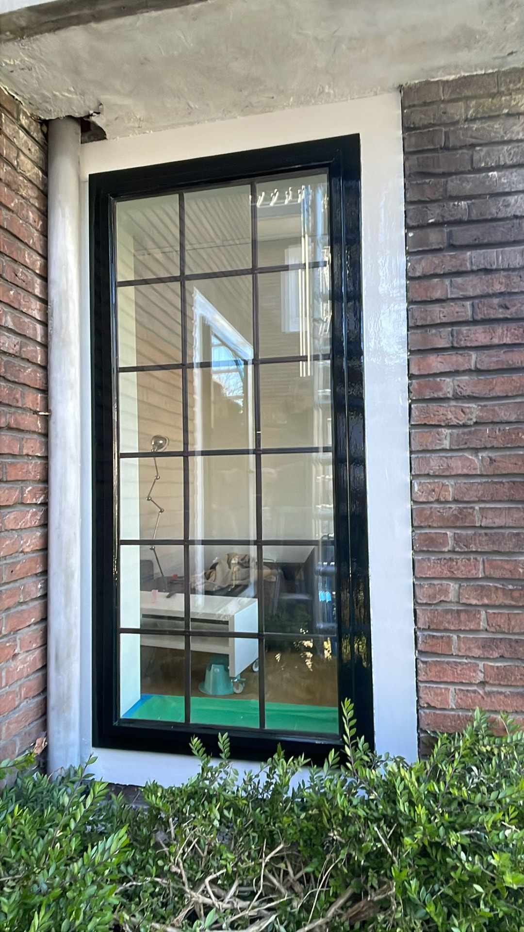 Zwart gelakt raamkozijn met roeden na afronding van het schilderwerk